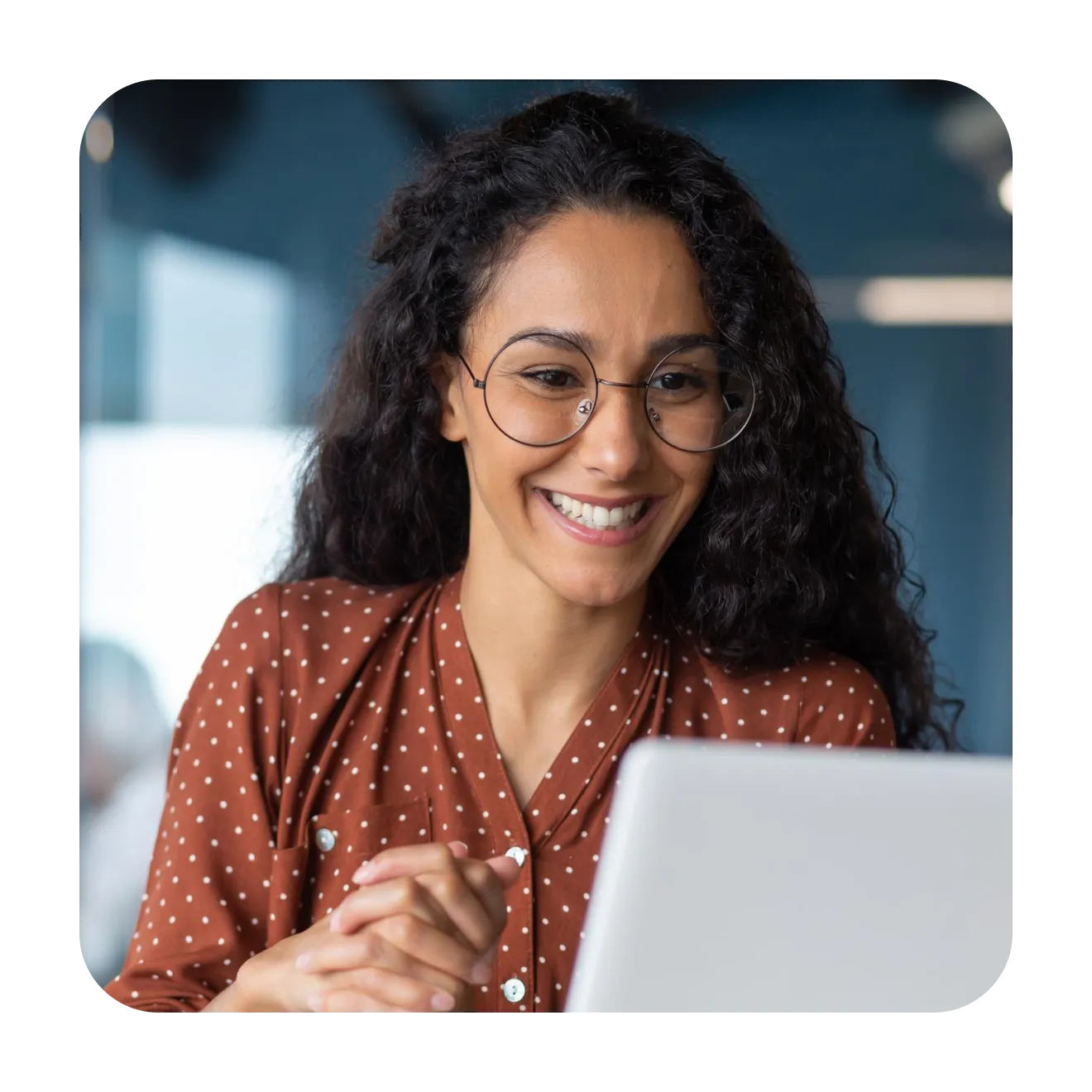 Smiling woman in glasses working at a laptop